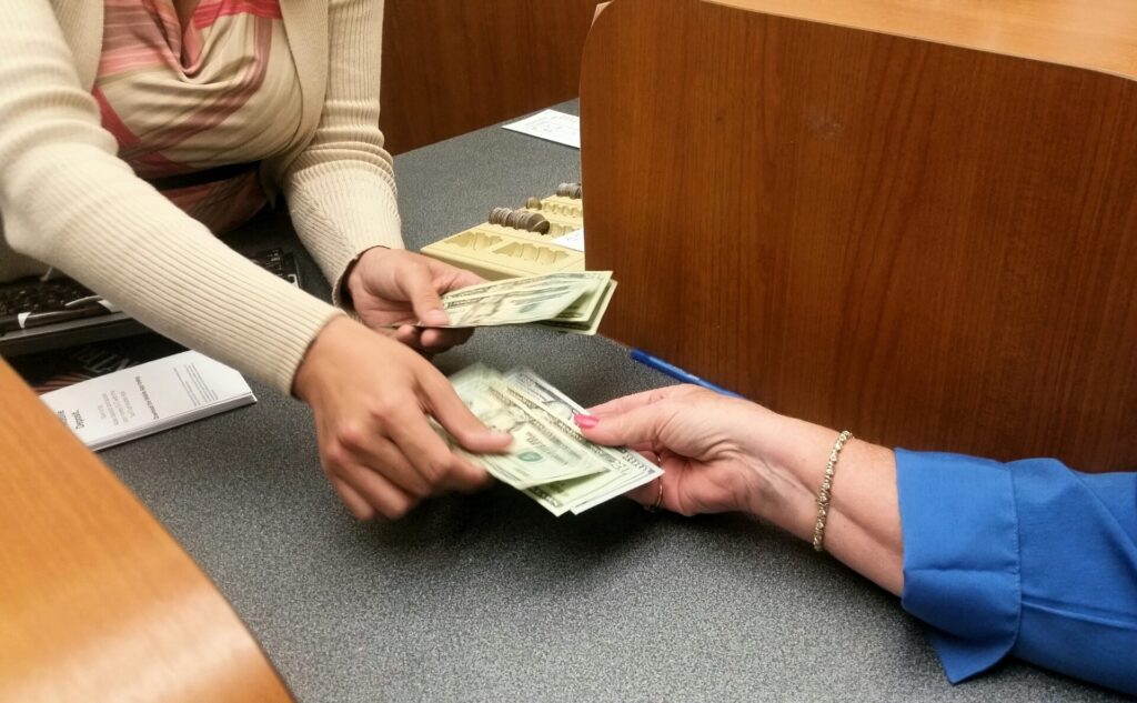 womans hand reaches for money from teller at the b 2022 11 12 09 50 46 utc